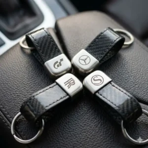 Custom engraved automotive key rings featuring minimalist car brand logos on metal surfaces.