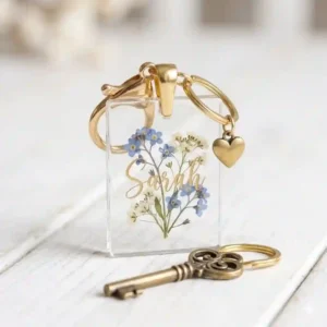 A clear rectangular acrylic key chain with name printed in gold lettering.