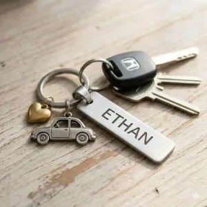 A stainless steel car key chain with name and a small vehicle charm attached to a key fob.